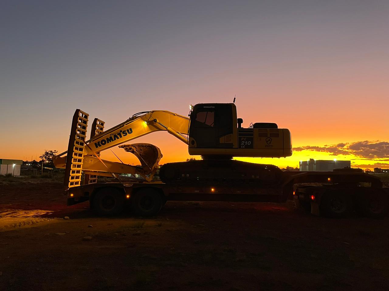 Escavadeira em obra de terraplenagem ao entardecer
